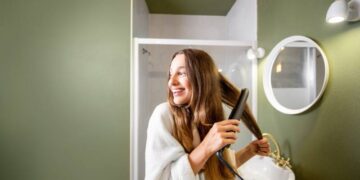 Woman straightening hair in the bathroom