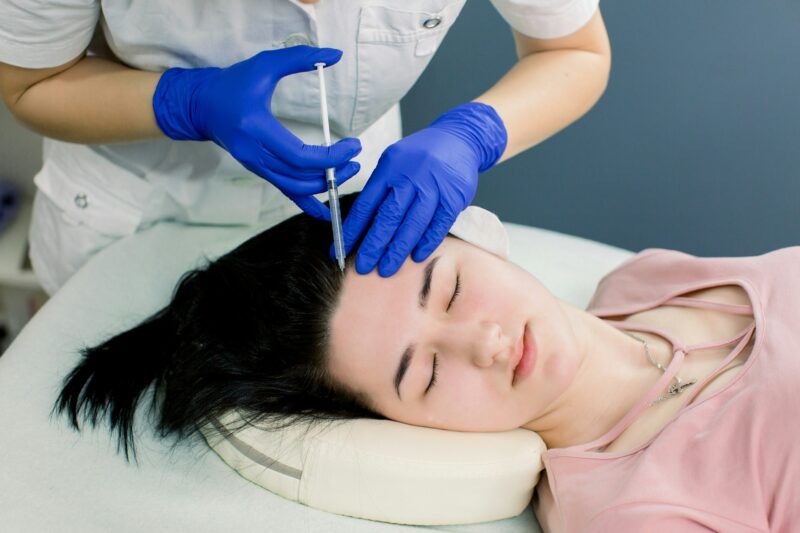 Hair mesotherapy or hair transplant: a beautician doctor makes injections in the head of a woman for