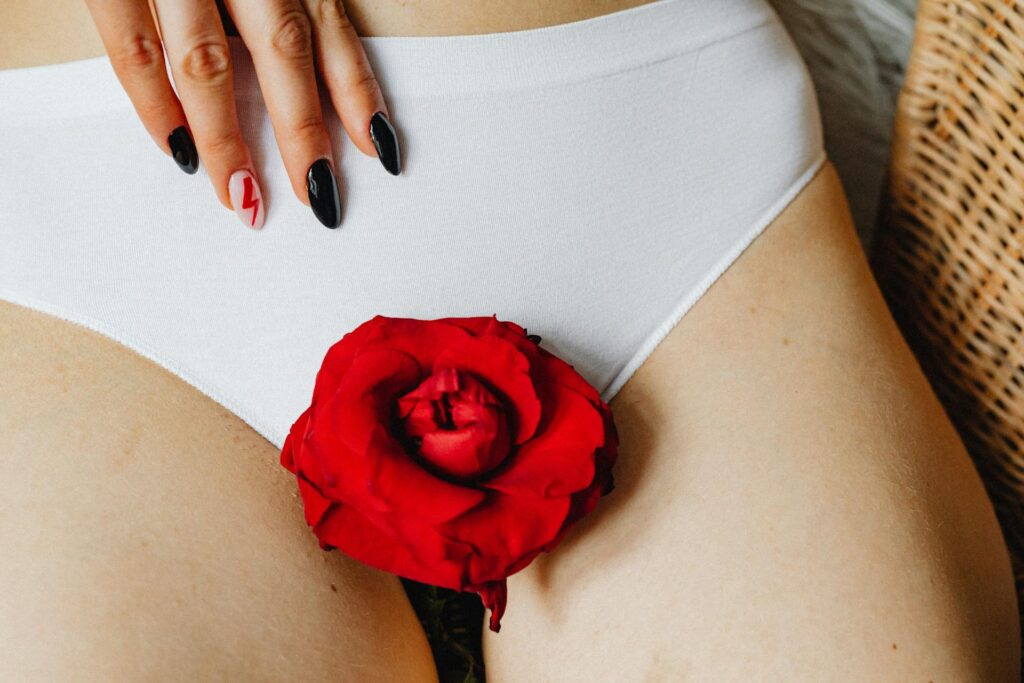 Close em parte do corpo feminino com flor vermelha sobre lingerie branca