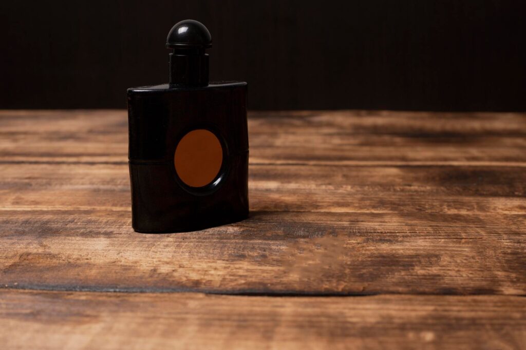 Frasco de perfume masculino na cor preta sobre mesa de madeira rústica, com fundo escuro e iluminação suave