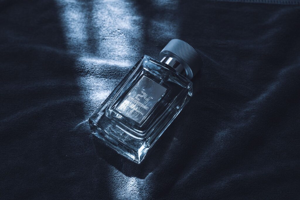 Qual perfume masculino mais vendido? Veja o ranking Frasco de perfume masculino em vidro sobre tecido escuro com iluminação azulada