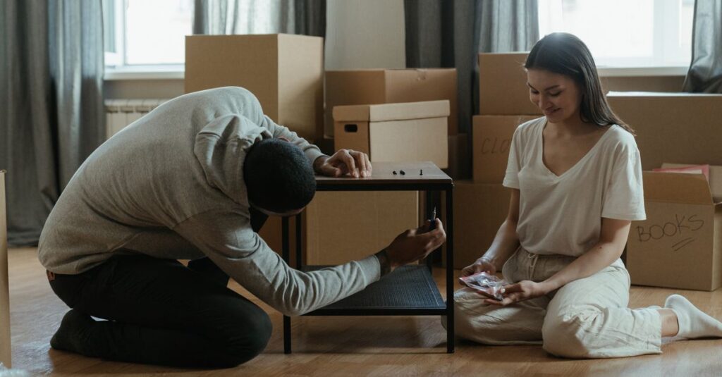 Um homem e uma mulher montando uma mesa em meio a caixas de mudança.